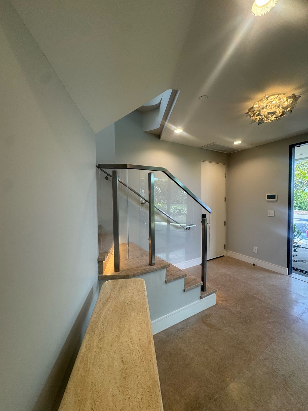Modern interior entry with a glass-rail staircase and soft gray painted walls and ceiling