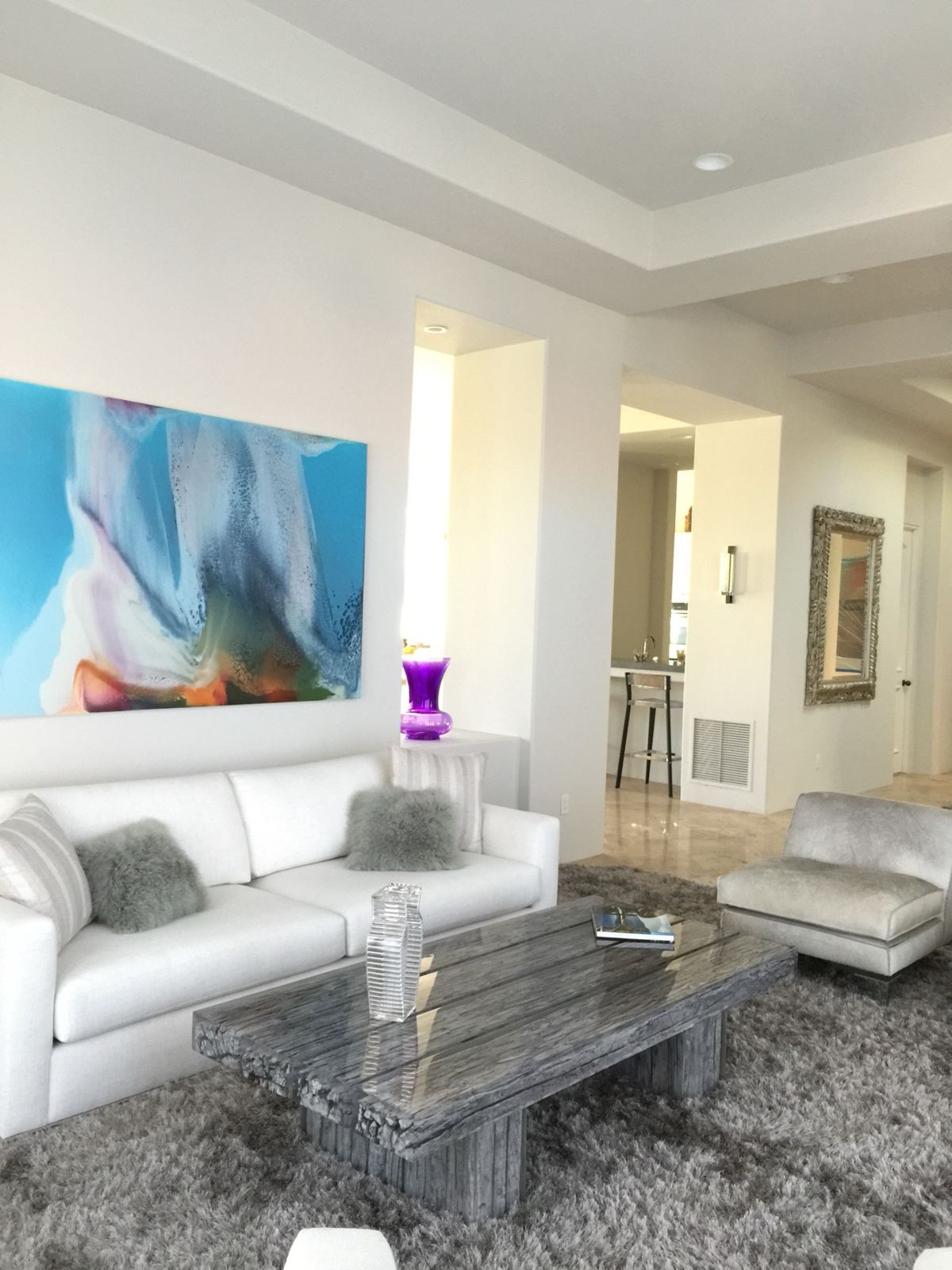 Bright living room with freshly painted white walls and ceiling and a large colorful abstract painting above the sofa