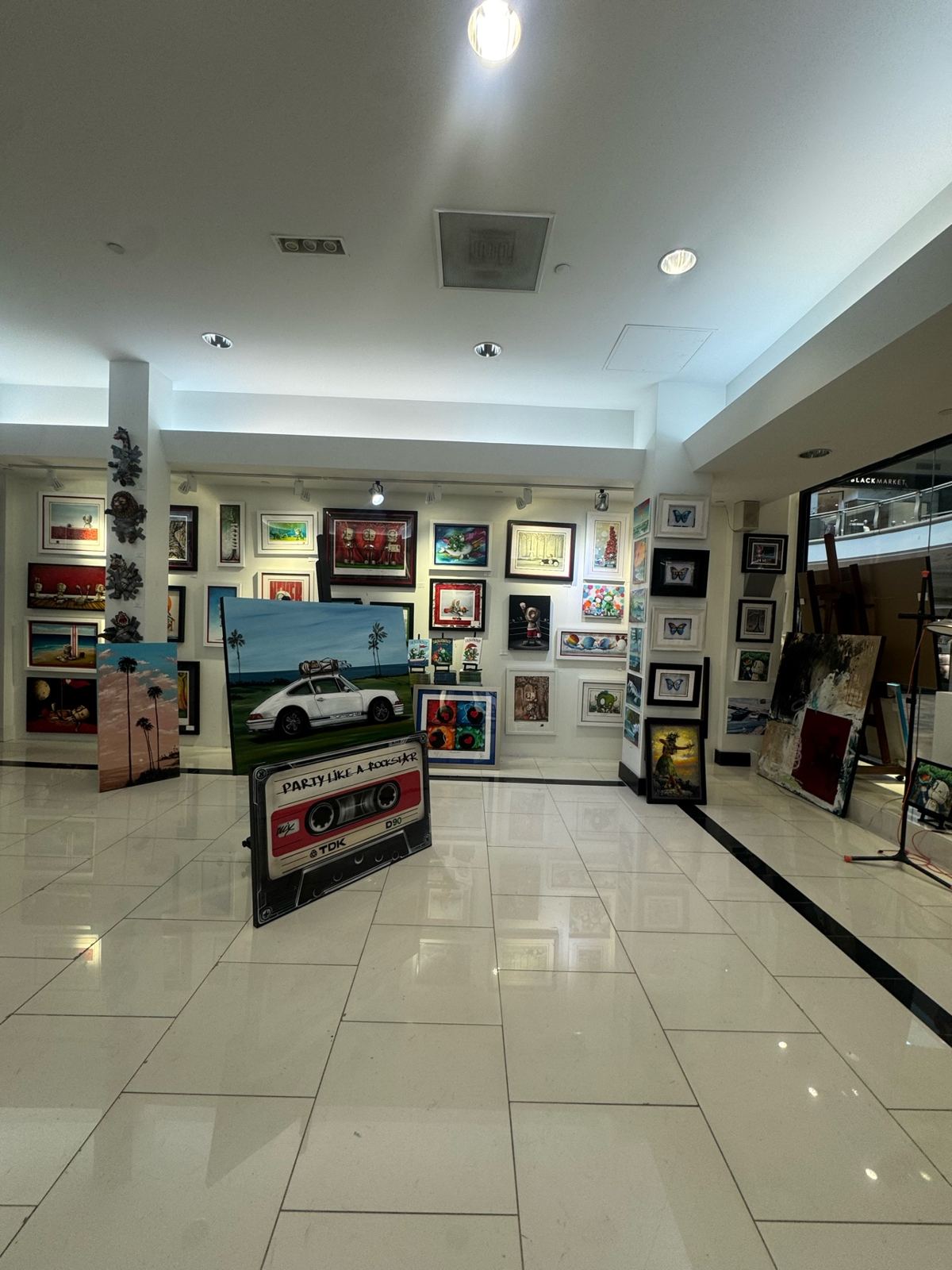 Fine art gallery interior with white walls and ceiling, track lighting, and artwork on display