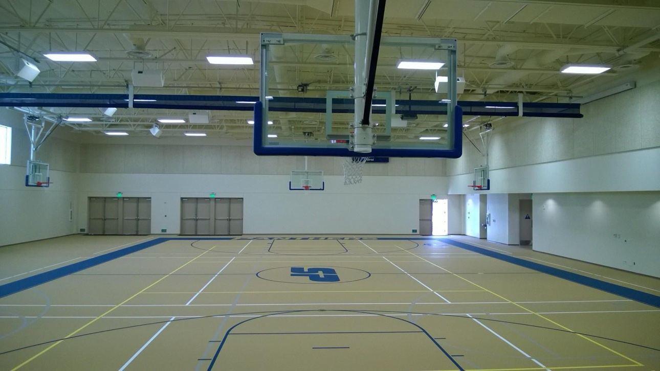 School gymnasium and basketball court with freshly painted cream walls and ceiling, viewed from center court