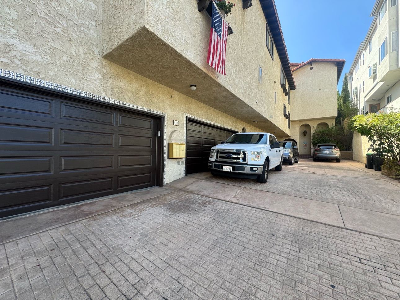 The same two garage doors finished in dark brown, seen across a wide paver driveway