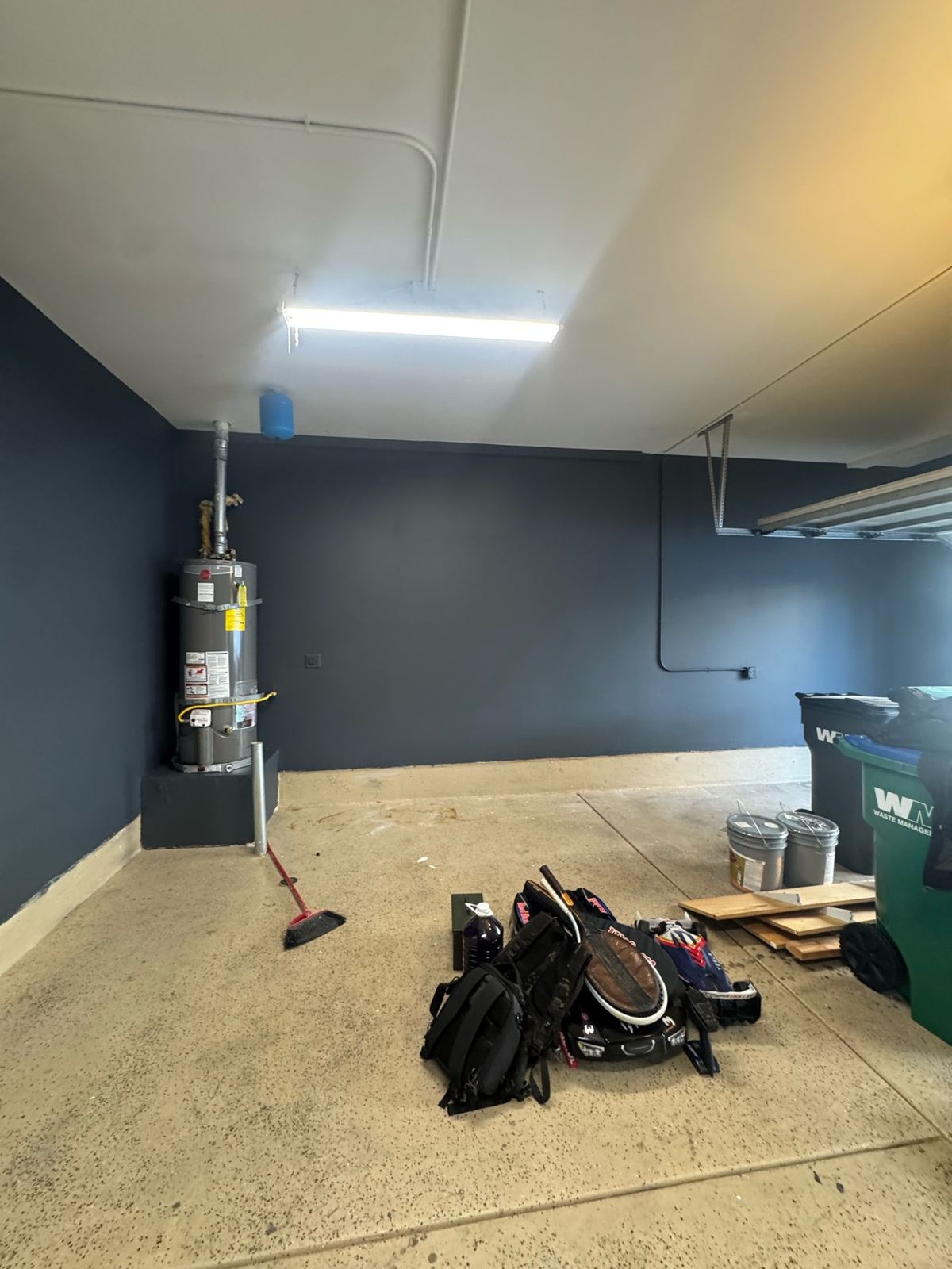 Finished garage with deep slate-blue painted walls, white ceiling, and concrete floor by the water heater