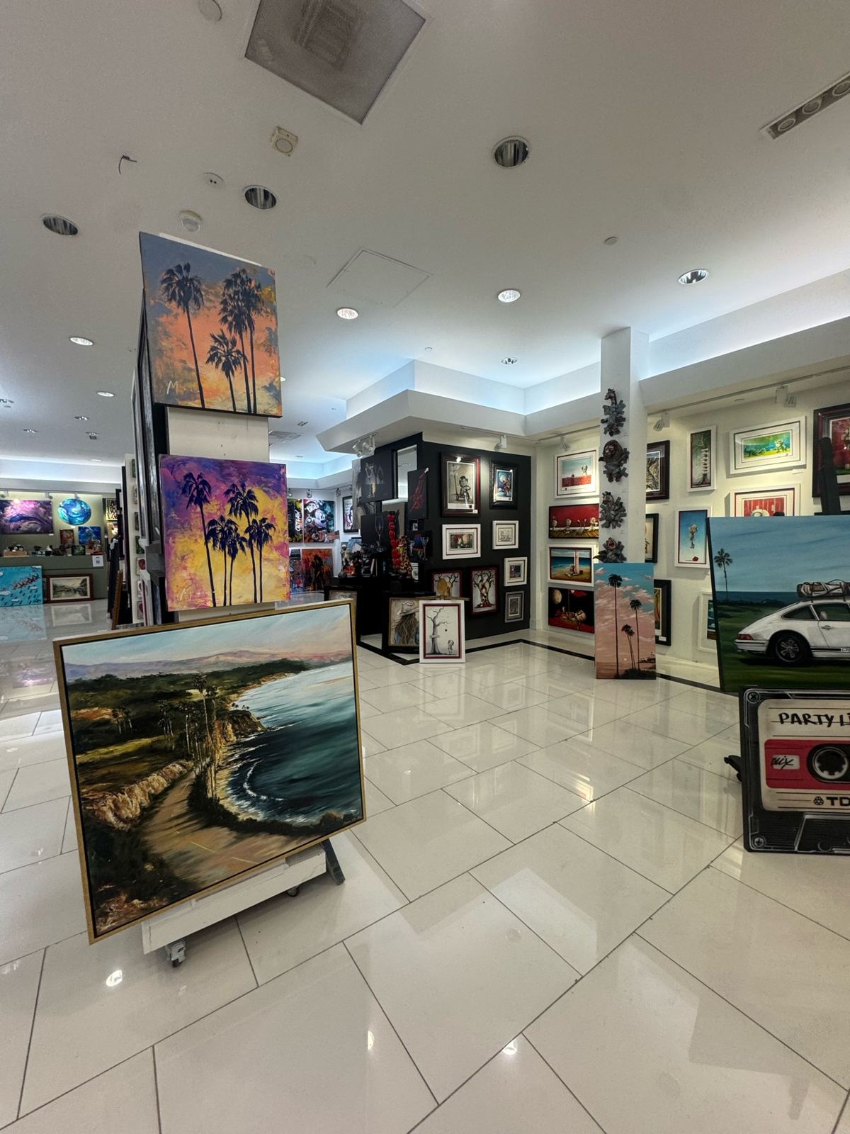 Second view of a fine art gallery interior with painted walls, a black accent wall, and coastal artwork