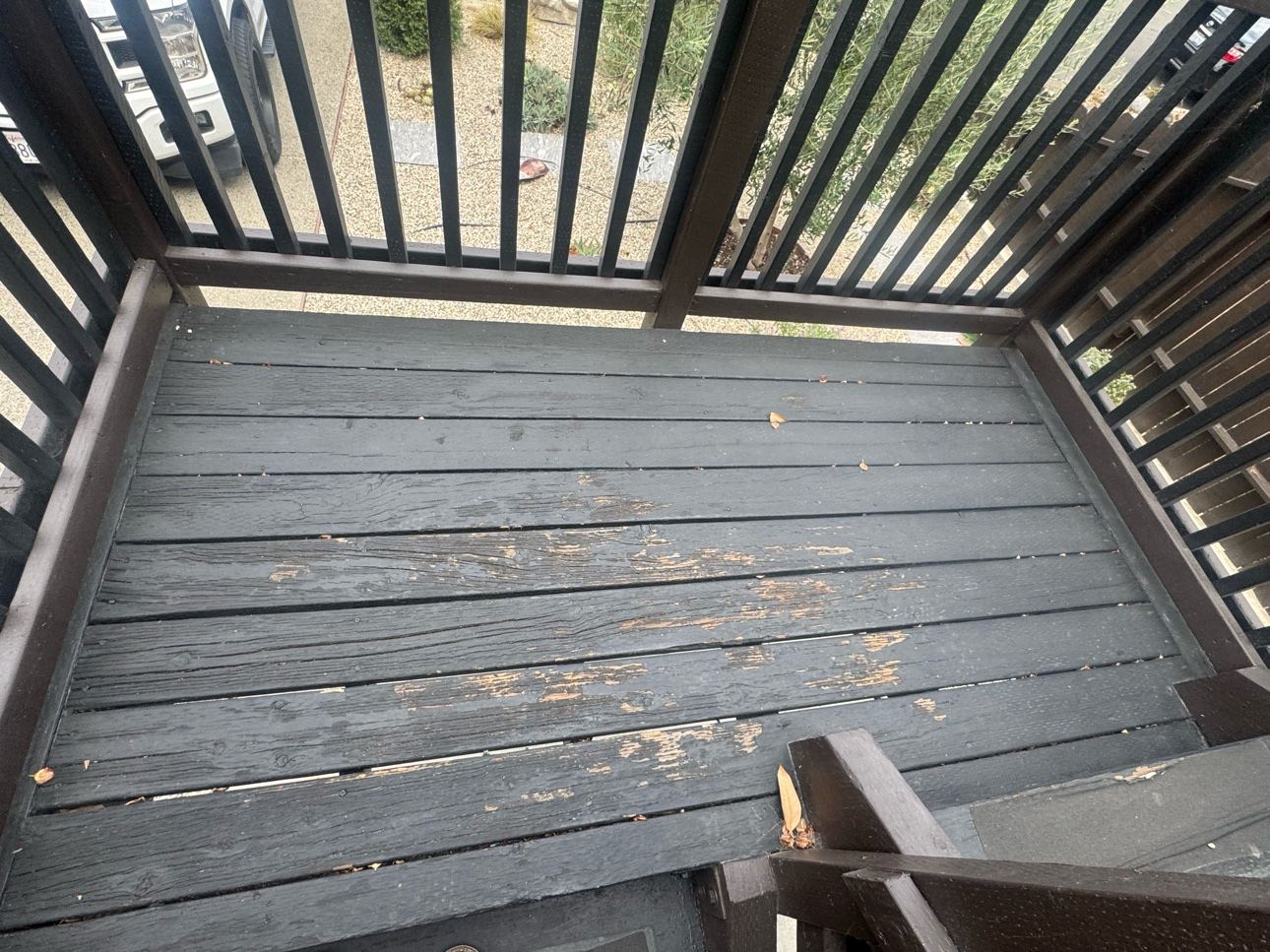 Before photo of a black deck with peeling, worn coating exposing bare wood