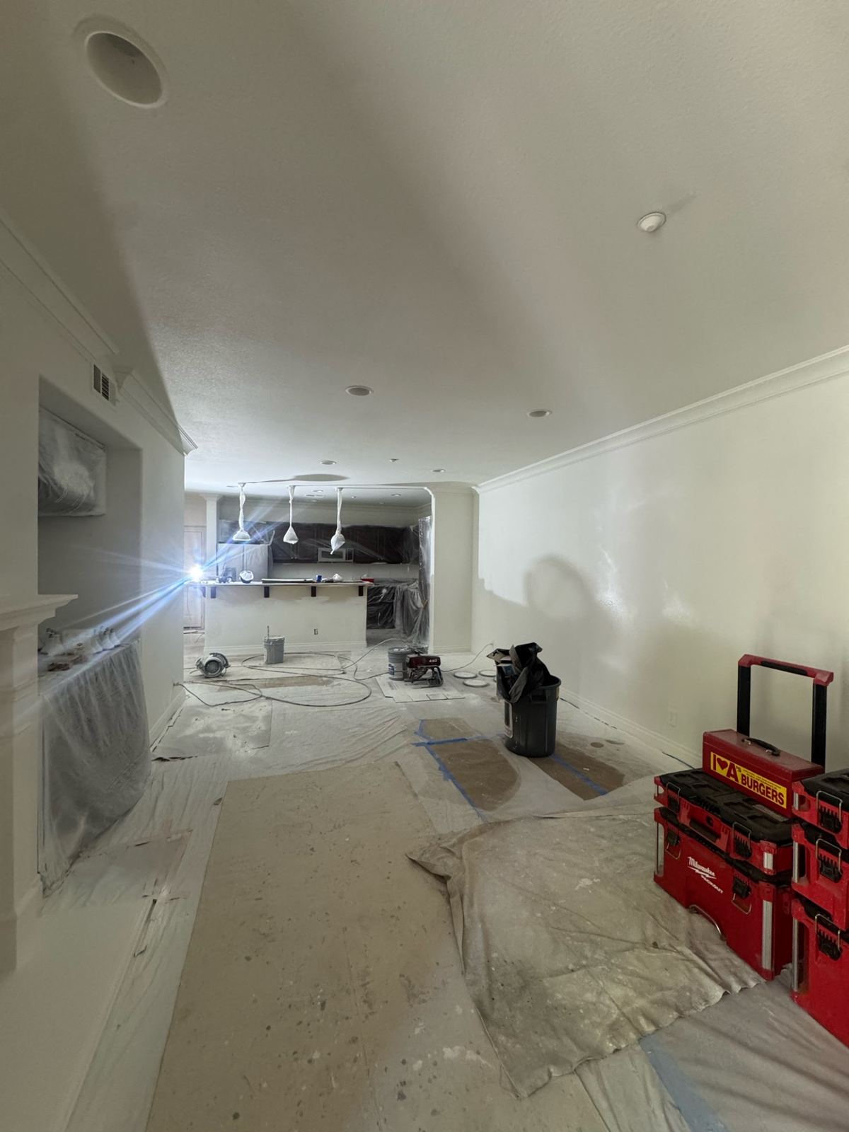 Living room and kitchen masked off with drop cloths down during an interior paint job