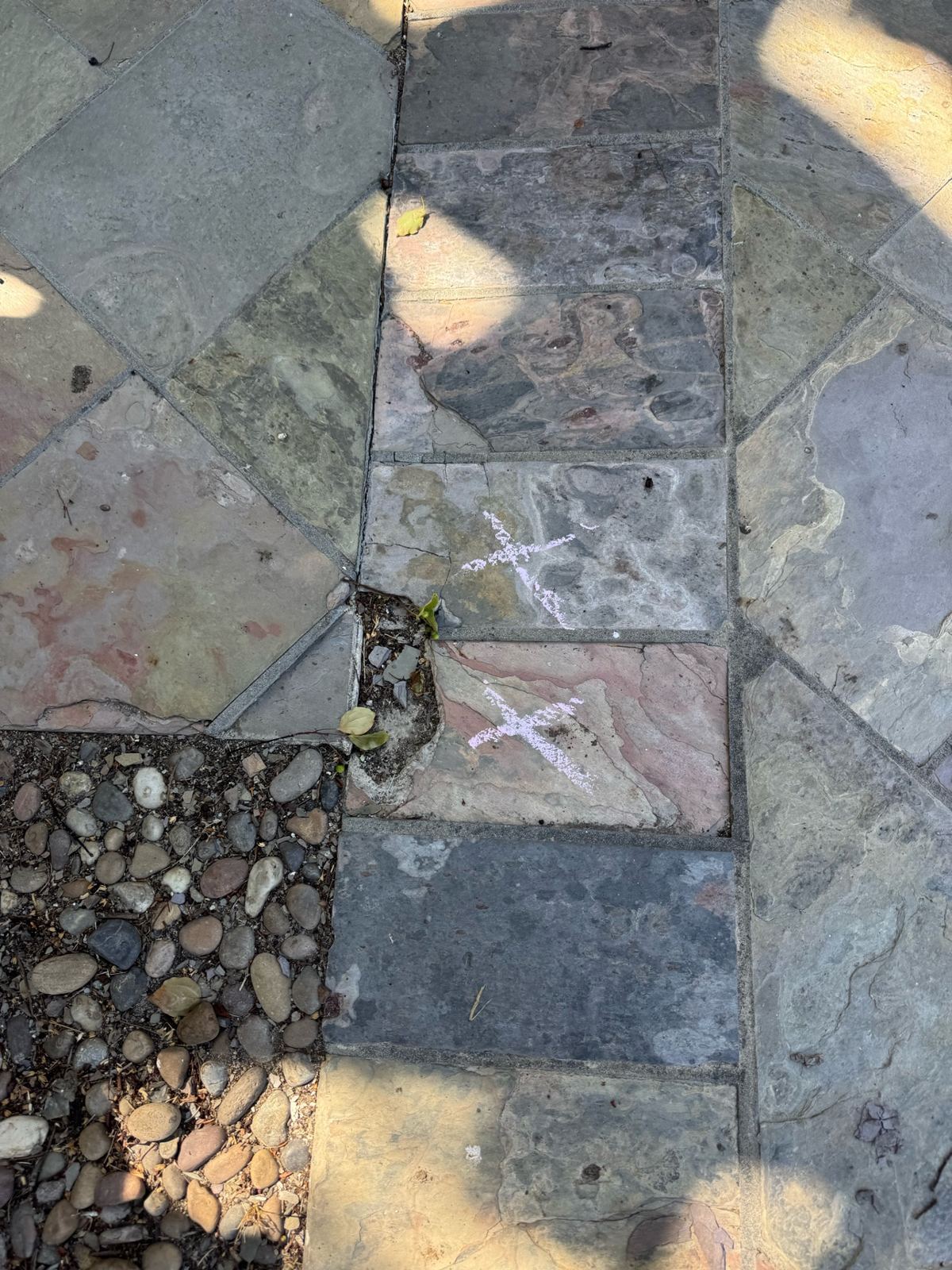 Before photo of slate driveway tiles marked with chalk X's for replacement, with one tile missing